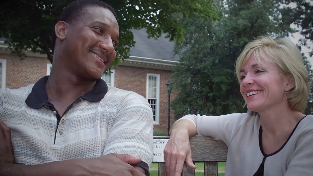 Ronald Cotton and Jennifer Thompson sitting together on a bench, smiling during a conversation years after his exoneration