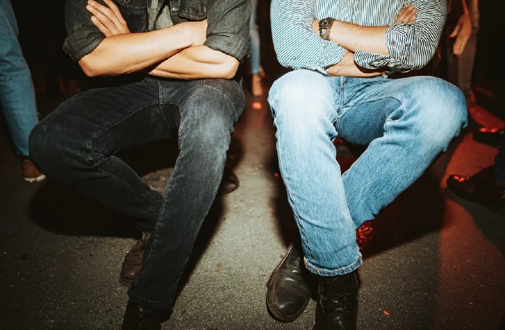 Two seated men with crossed legs playing the mystery-based party game Crossed, Uncrossed
