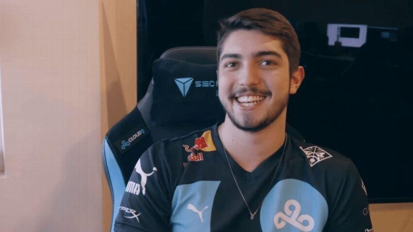 Jukes, the professional gamer and streamer, smiling while seated in a gaming chair with sponsor logos visible on his jersey