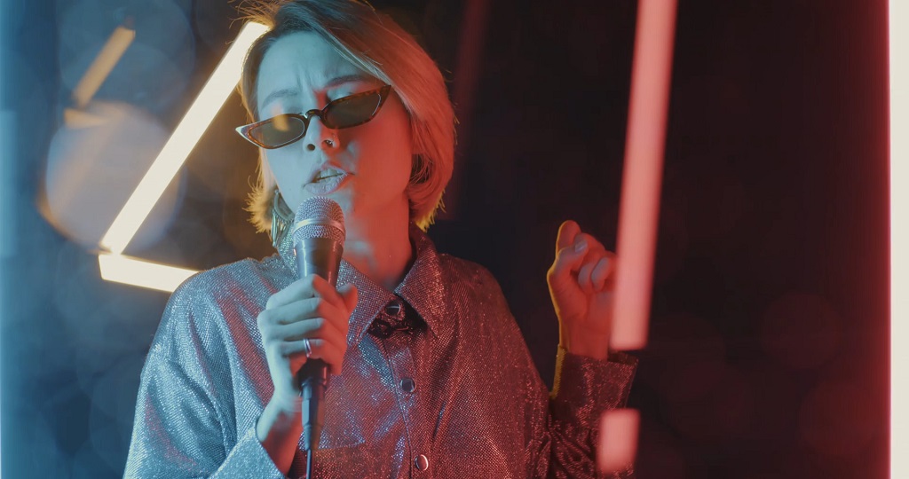 Woman singing into a microphone under neon lights during a karaoke performance