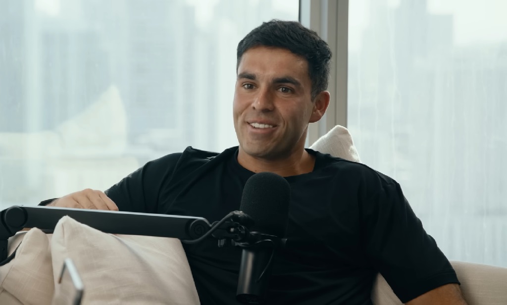 Kyle Forgeard from Nelk Boys sitting in a modern setting, speaking into a podcast microphone