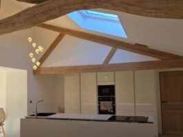 A modern kitchen with a rustic charm, showcasing exposed wooden beams and a skylight