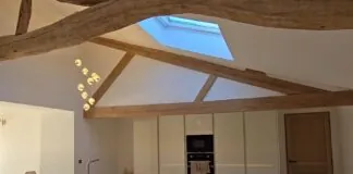A modern kitchen with a rustic charm, showcasing exposed wooden beams and a skylight