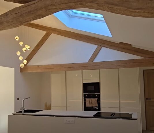 A modern kitchen with a rustic charm, showcasing exposed wooden beams and a skylight