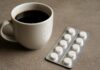 An image showing a cup of coffee and a package of medicines next to each other.