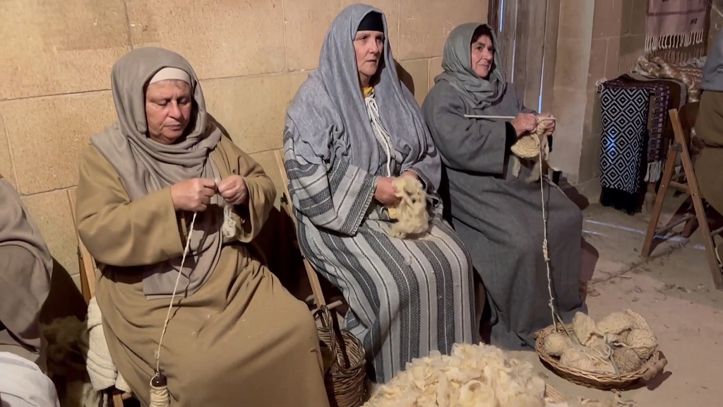 Women in traditional robes demonstrating wool spinning and weaving, part of Malta’s famous live Nativity village in Gozo