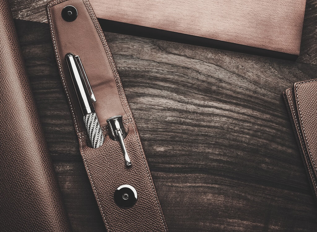 Leather pen case with fountain pen and minimalist design on wooden surface