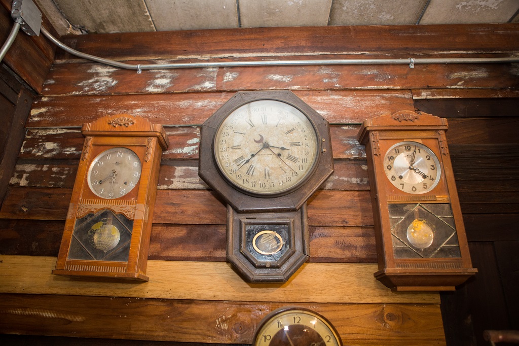 Collection of vintage wooden wall clocks mounted on rustic interior wall