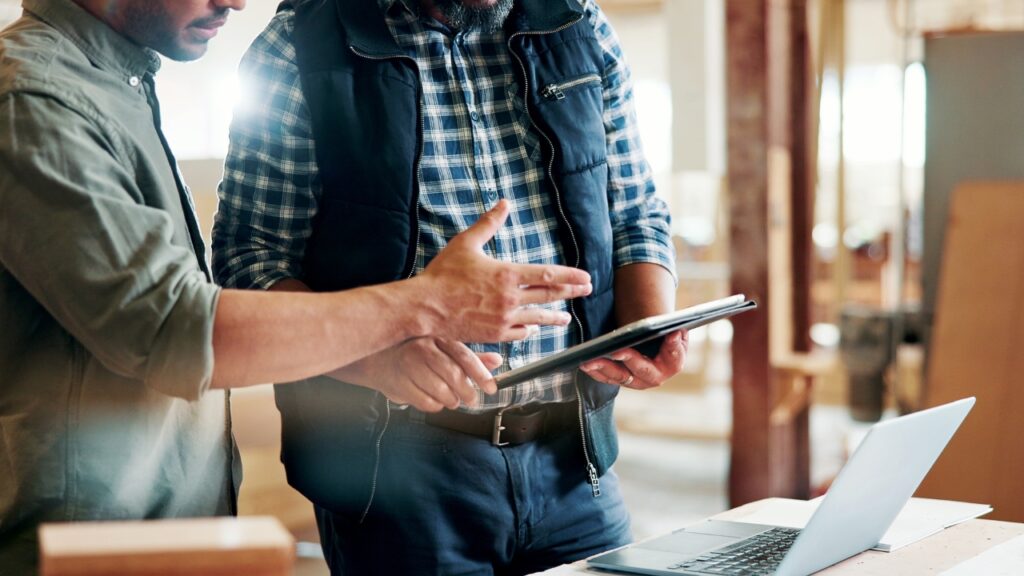 Contractors review supplier delays on a tablet inside an active construction site