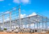 Steel frame construction site with stacked pipes showing material shortages before project work begins