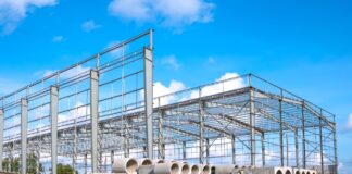 Steel frame construction site with stacked pipes showing material shortages before project work begins