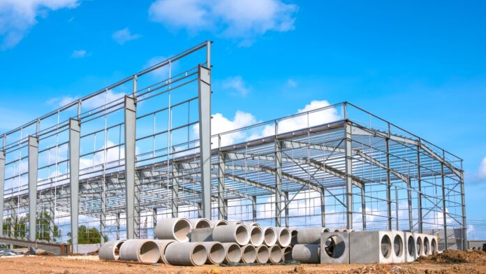 Steel frame construction site with stacked pipes showing material shortages before project work begins