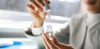 A person measures CBD oil with a dropper in a small glass bottle