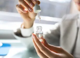 A person measures CBD oil with a dropper in a small glass bottle