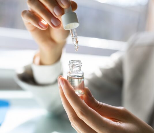 A person measures CBD oil with a dropper in a small glass bottle