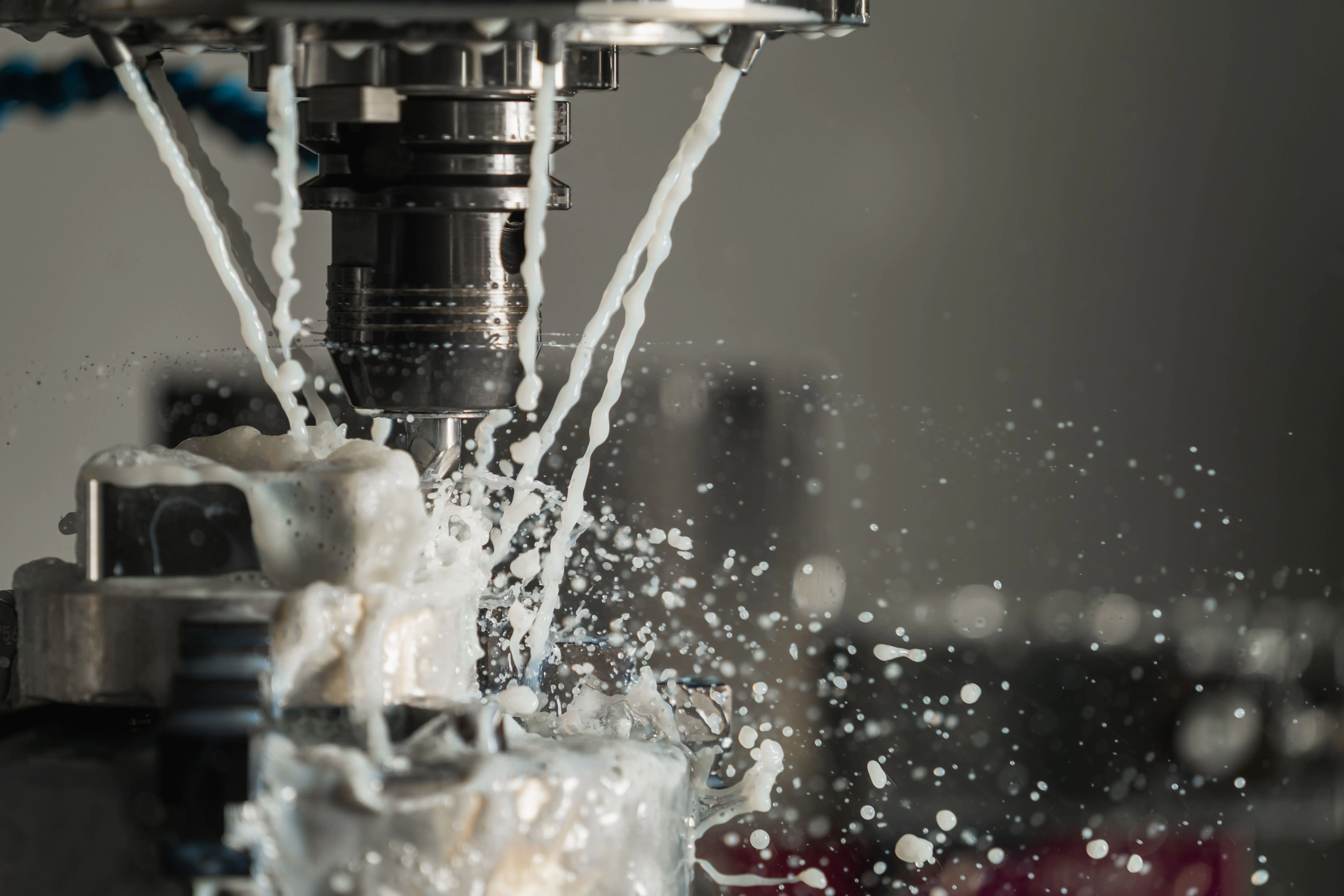 Close-up of a CNC machine with coolant spraying during a metalwork operation
