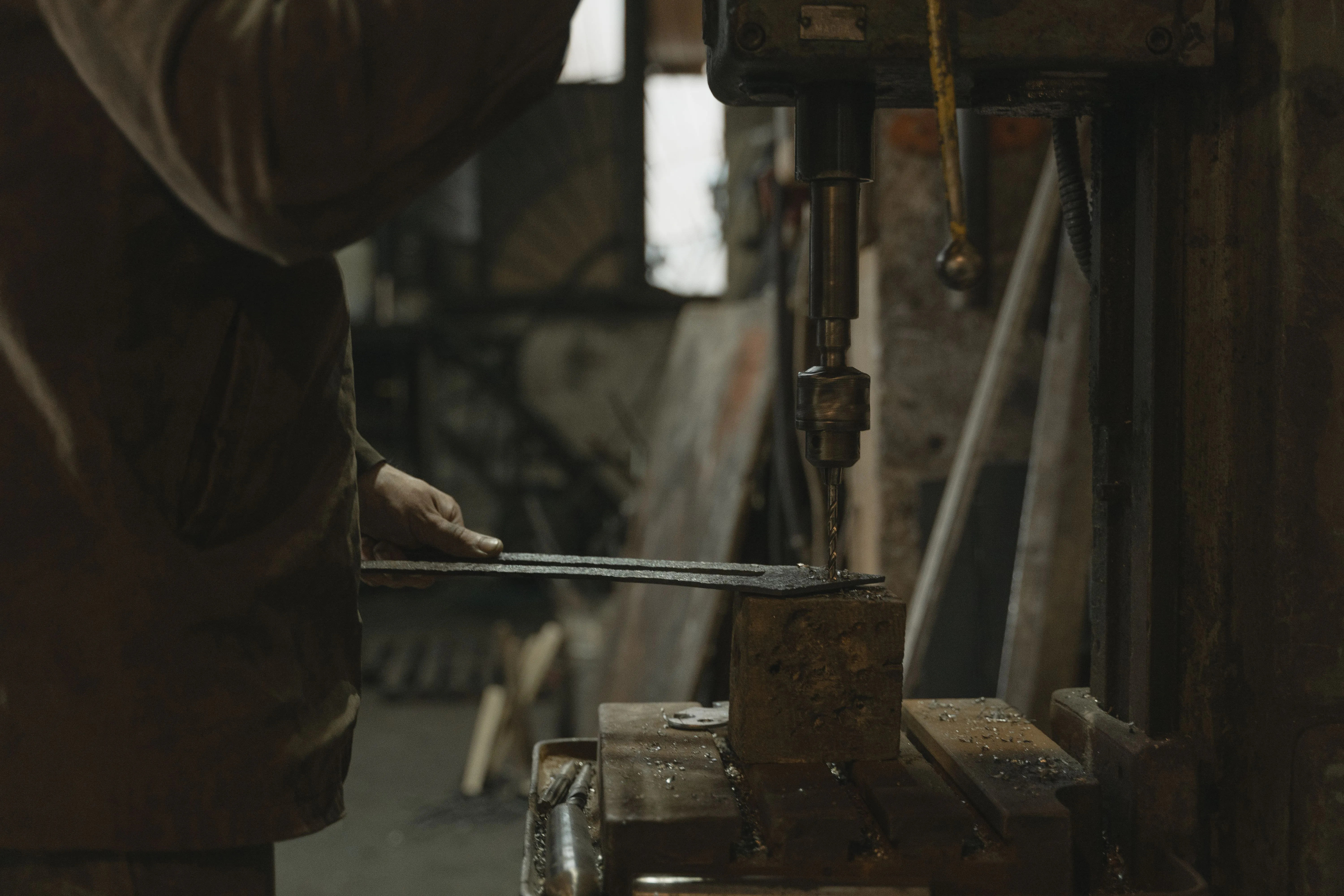 Craftsman using a drill press in a small indoor workshop