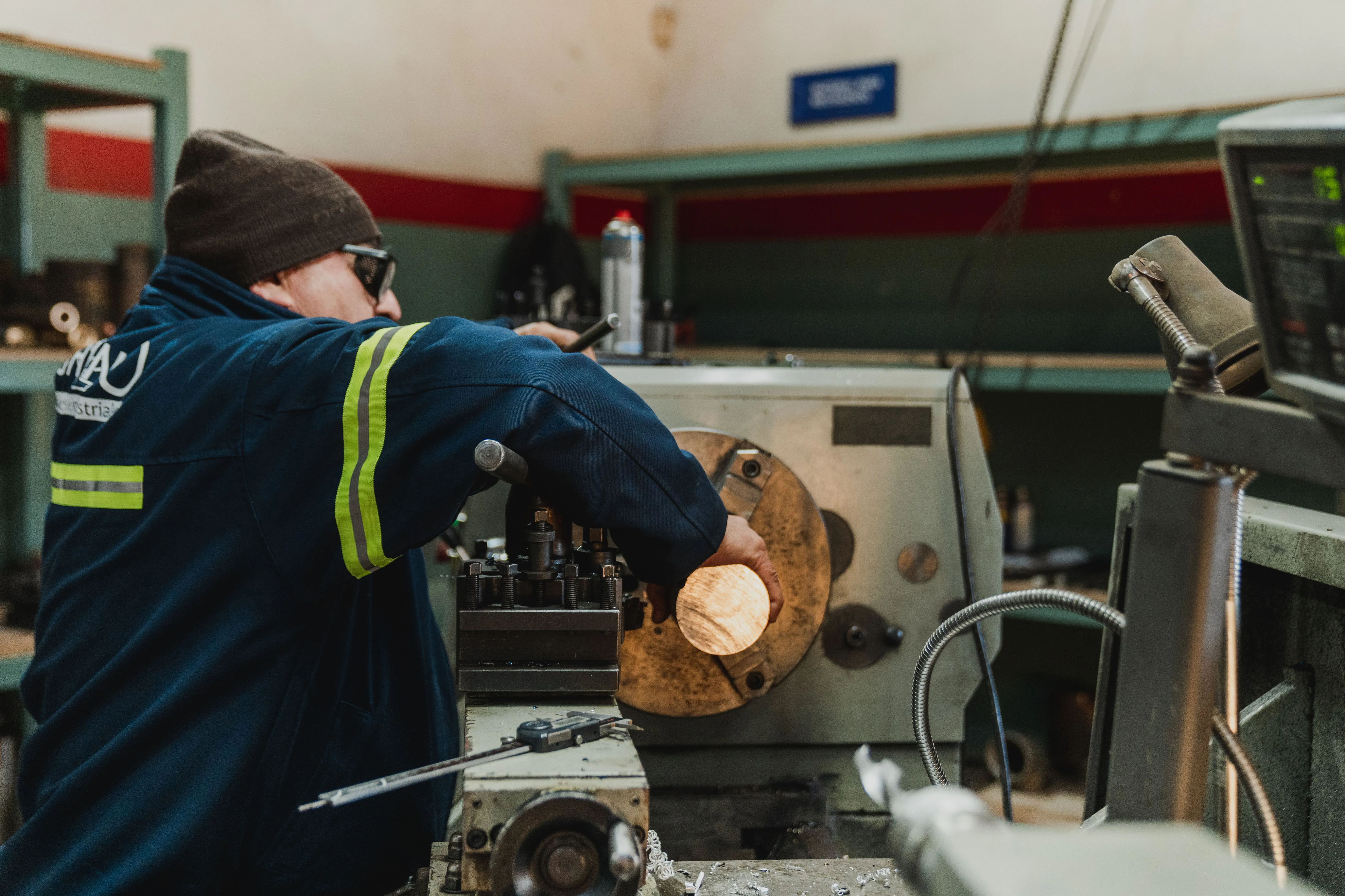 Industrial worker operating a lathe in a busy workshop